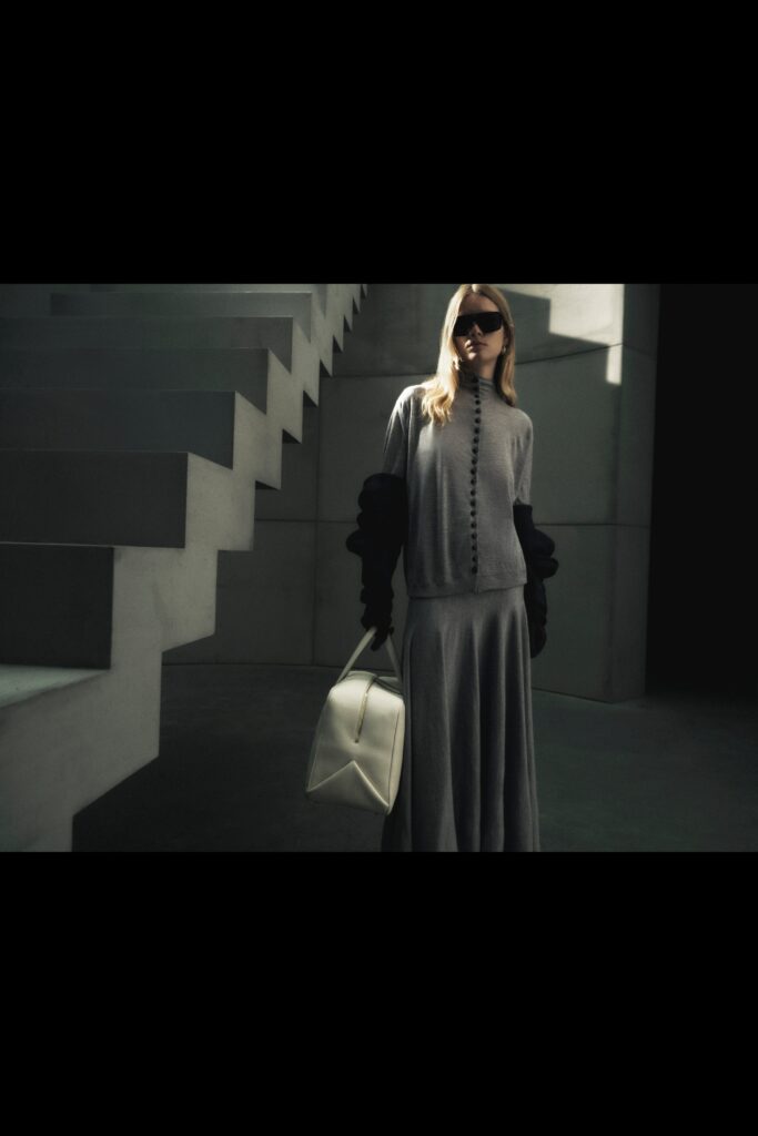A fitted gray long-sleeve dress with a V-neckline and asymmetric design detail.
