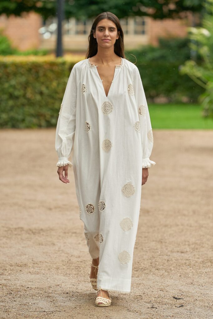 A relaxed white dress with long sleeves, a V-neckline, and embroidered details.