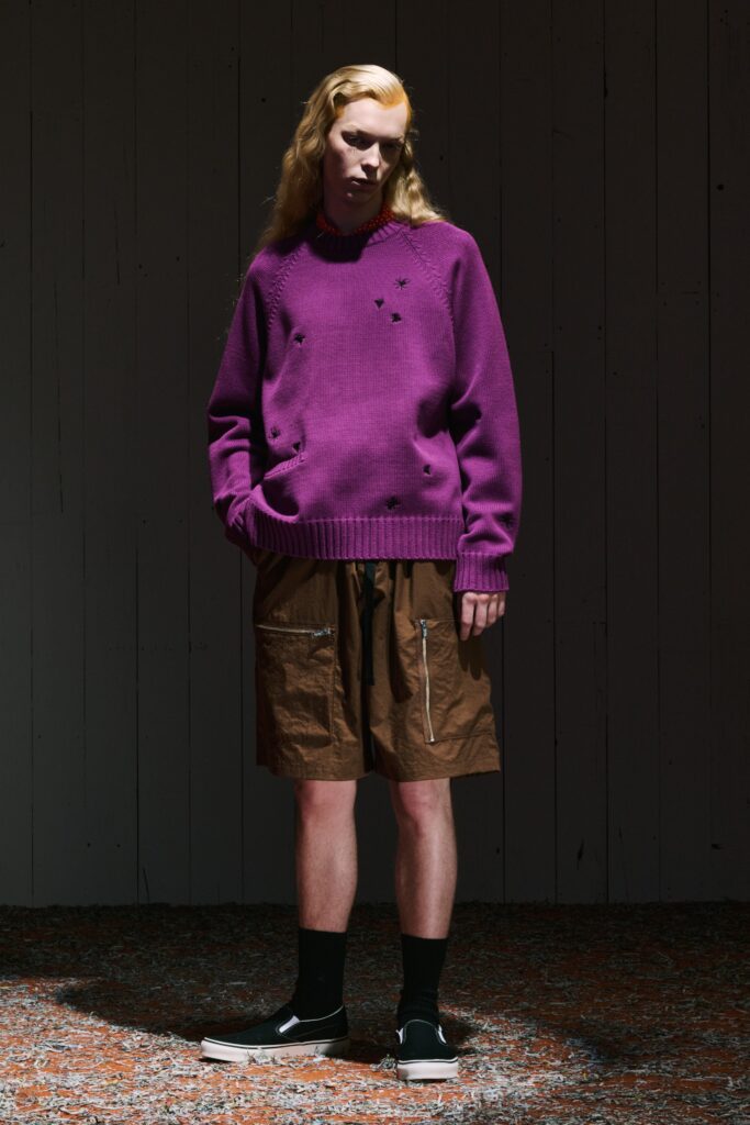 A relaxed purple long-sleeve sweater with embroidered details paired with high-waisted brown shorts.