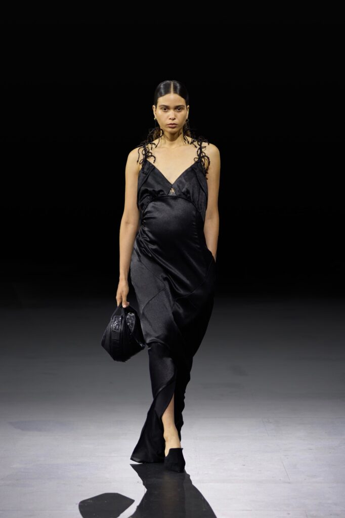 A fitted black silk sleeveless dress featuring a deep v-neckline and a stylish silhouette.