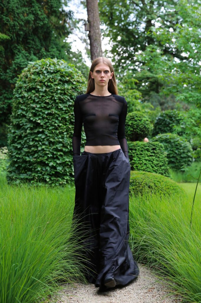 A fitted black sheer long-sleeve top paired with wide-leg black pants.