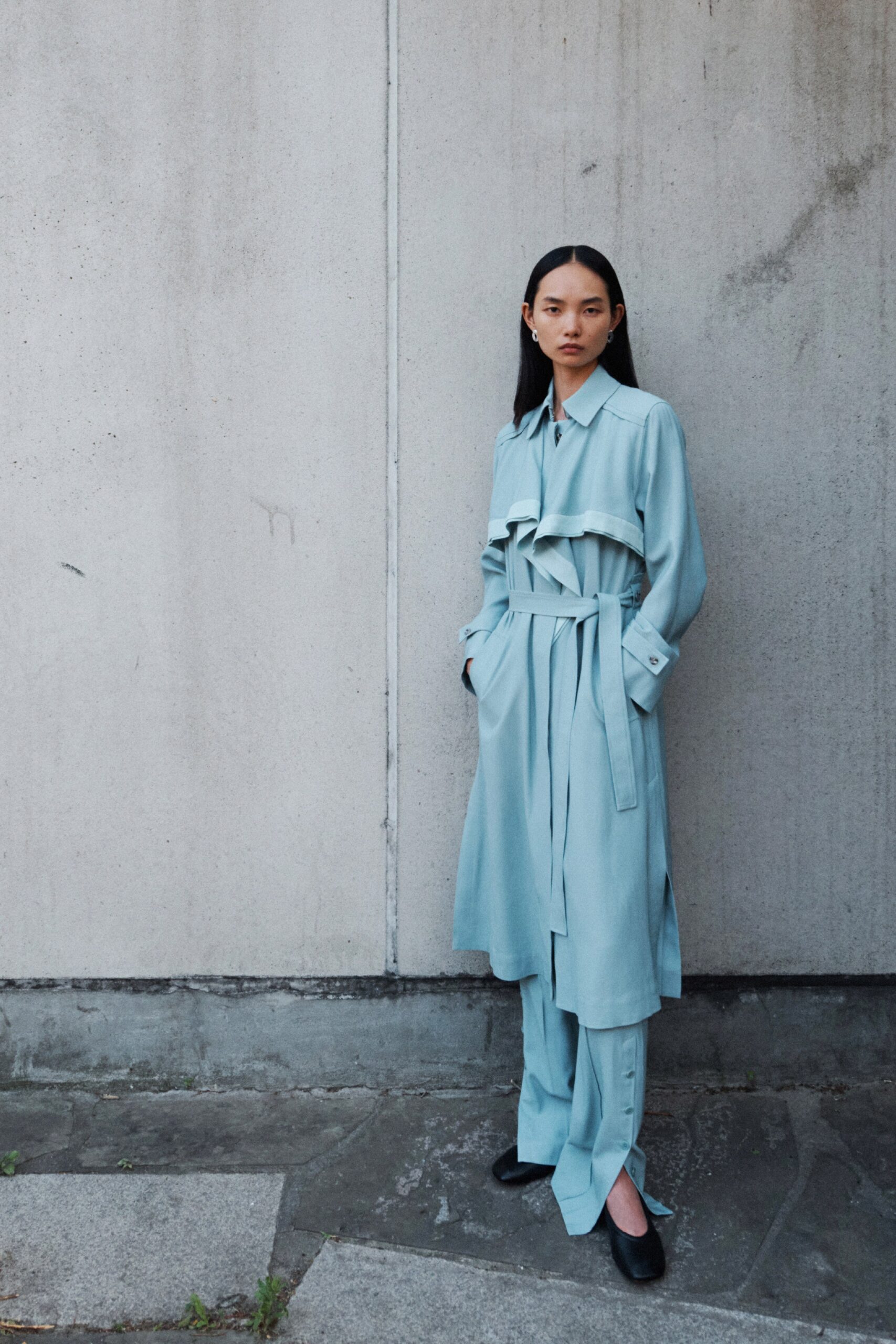 A relaxed blue cotton dress jacket with long sleeves and a belted layered design.