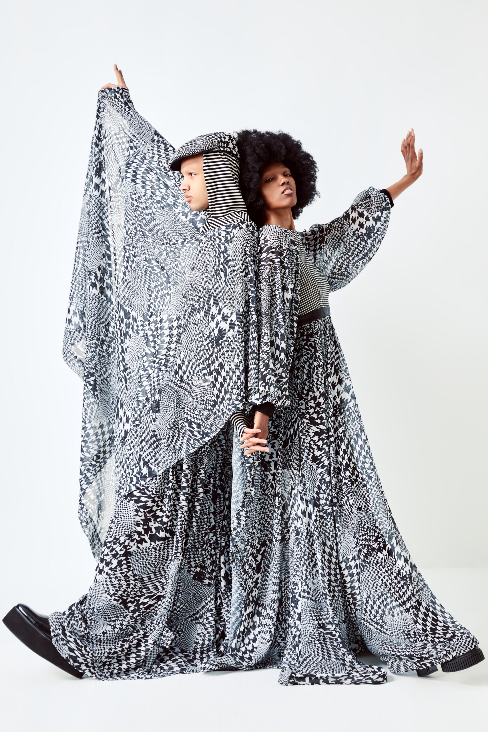 This relaxed dress features a high-neck and long sleeves, showcasing an intricate black and white print that creates a striking visual impact. The layered design adds depth and movement, making it a captivating piece that draws the eye with its bold patterns.