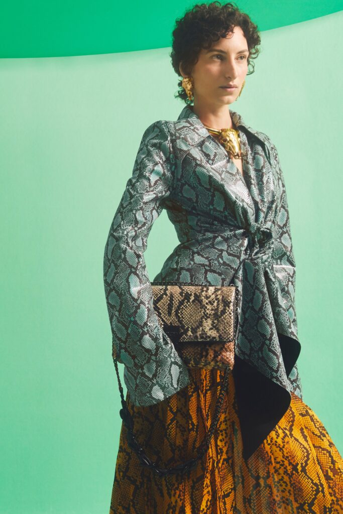 A fitted green printed blazer with long sleeves paired with a yellow asymmetric skirt.
