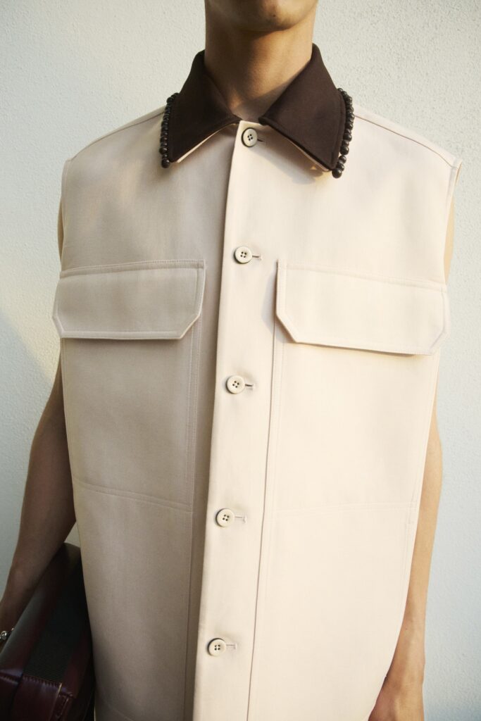 A relaxed beige cotton vest with a collared neckline and buttoned front.