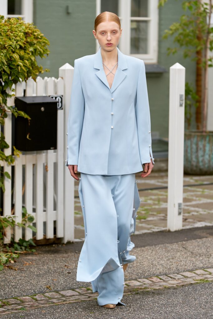 A fitted blue silk suit with long sleeves, a collared neckline, and an asymmetric design.