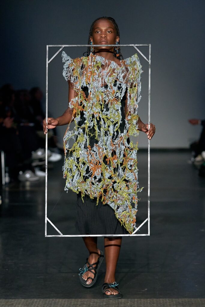 A relaxed black sleeveless dress with a V-neckline and asymmetric design details.