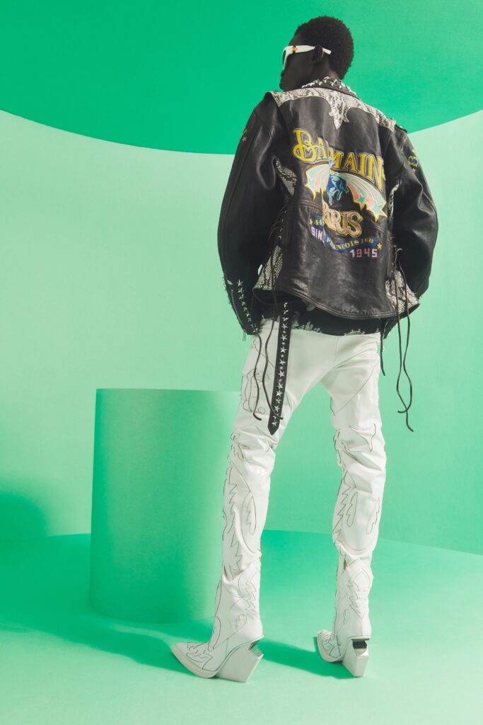 An oversized black leather jacket with embroidery paired with white denim pants.