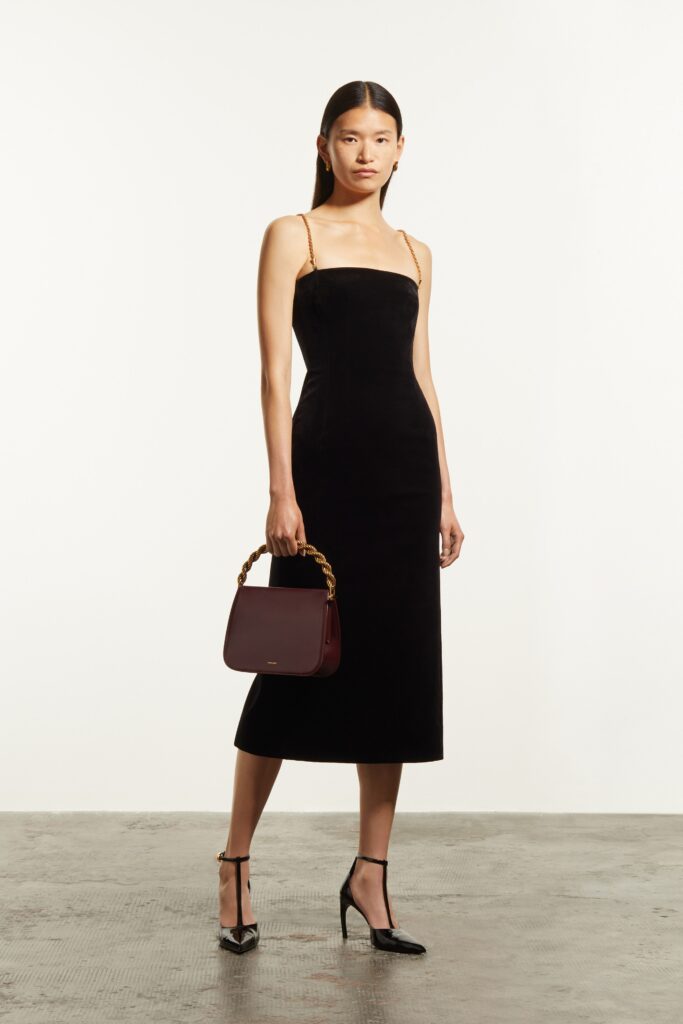A fitted black velvet sleeveless dress with a V-neckline and straight-leg silhouette.