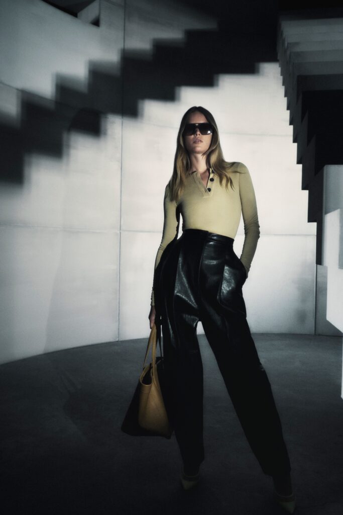 A fitted green long-sleeve top paired with high-waisted black leather pants.