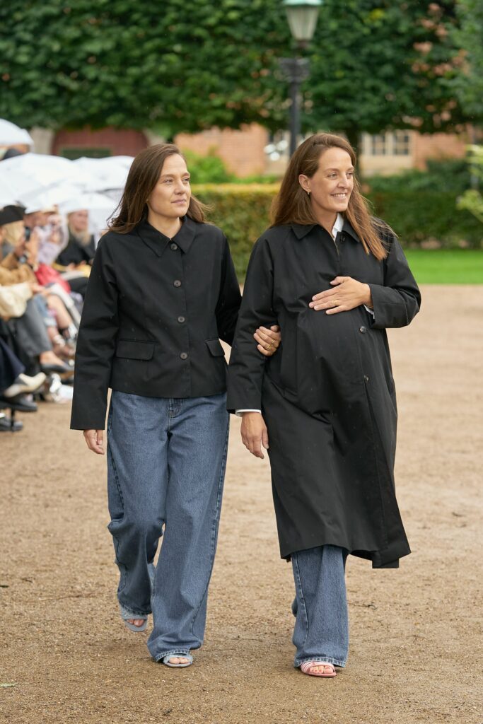 A relaxed black coat paired with blue straight-leg jeans for a casual look.
