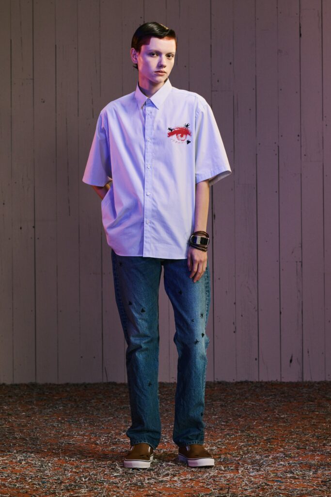 A relaxed white collared shirt with short sleeves paired with high-waisted blue jeans featuring embroidery.