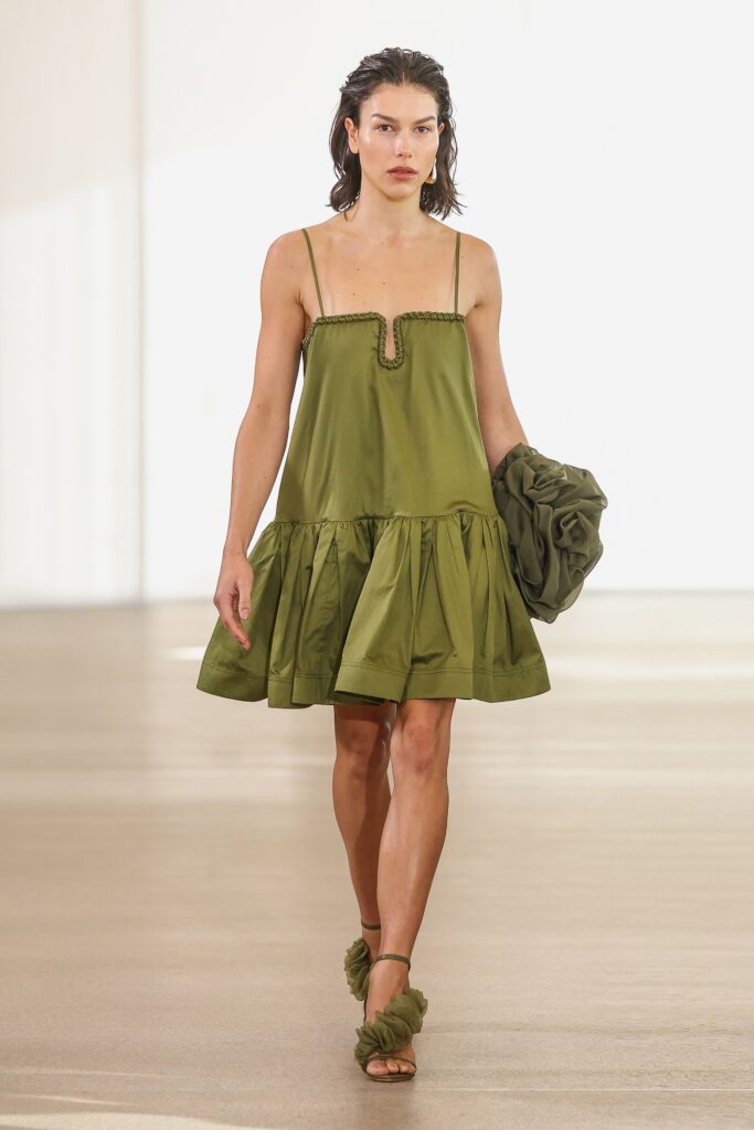 A fitted green silk sleeveless dress with a V-neckline and tiered design.