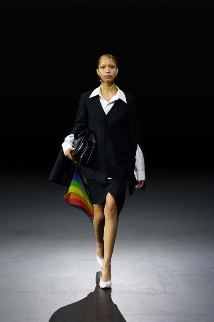 A black tailored blazer paired with an asymmetric black skirt, creating a sophisticated look.