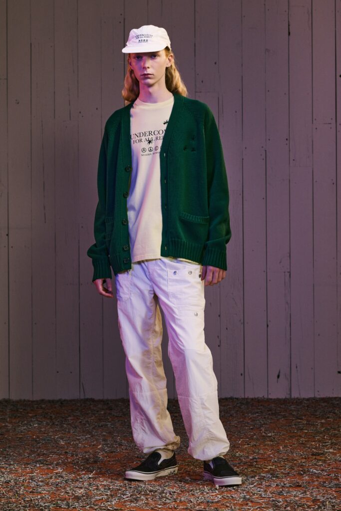 A relaxed green cardigan with long sleeves paired with white pants, featuring a buttoned design.