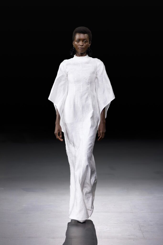 A fitted white silk dress with long sleeves and a sleek silhouette.