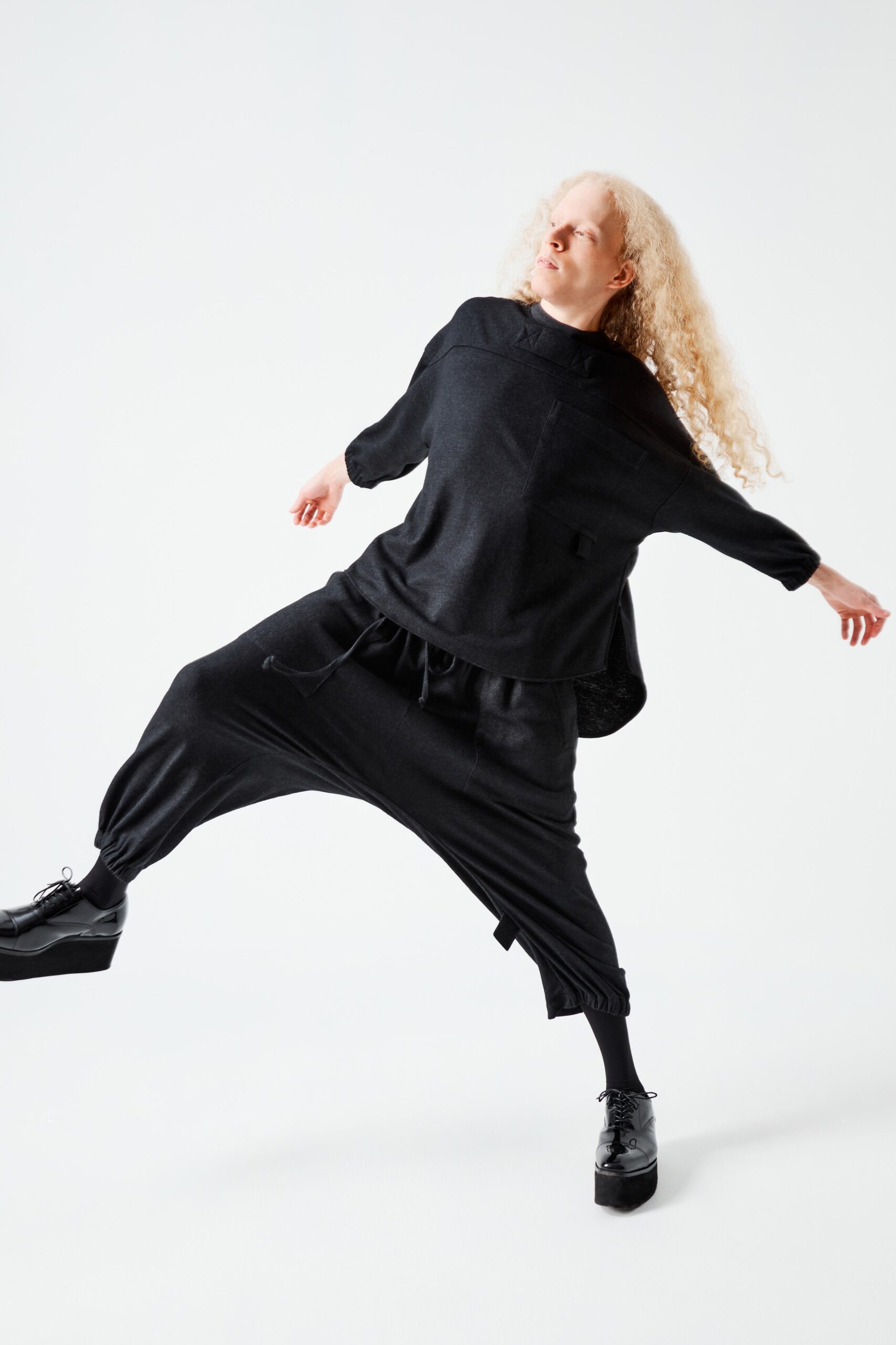 This ensemble features a relaxed black top with long sleeves and a unique collar, paired with equally relaxed pants that showcase an asymmetric silhouette. The combination creates a fluid movement, emphasizing comfort while maintaining a contemporary edge.