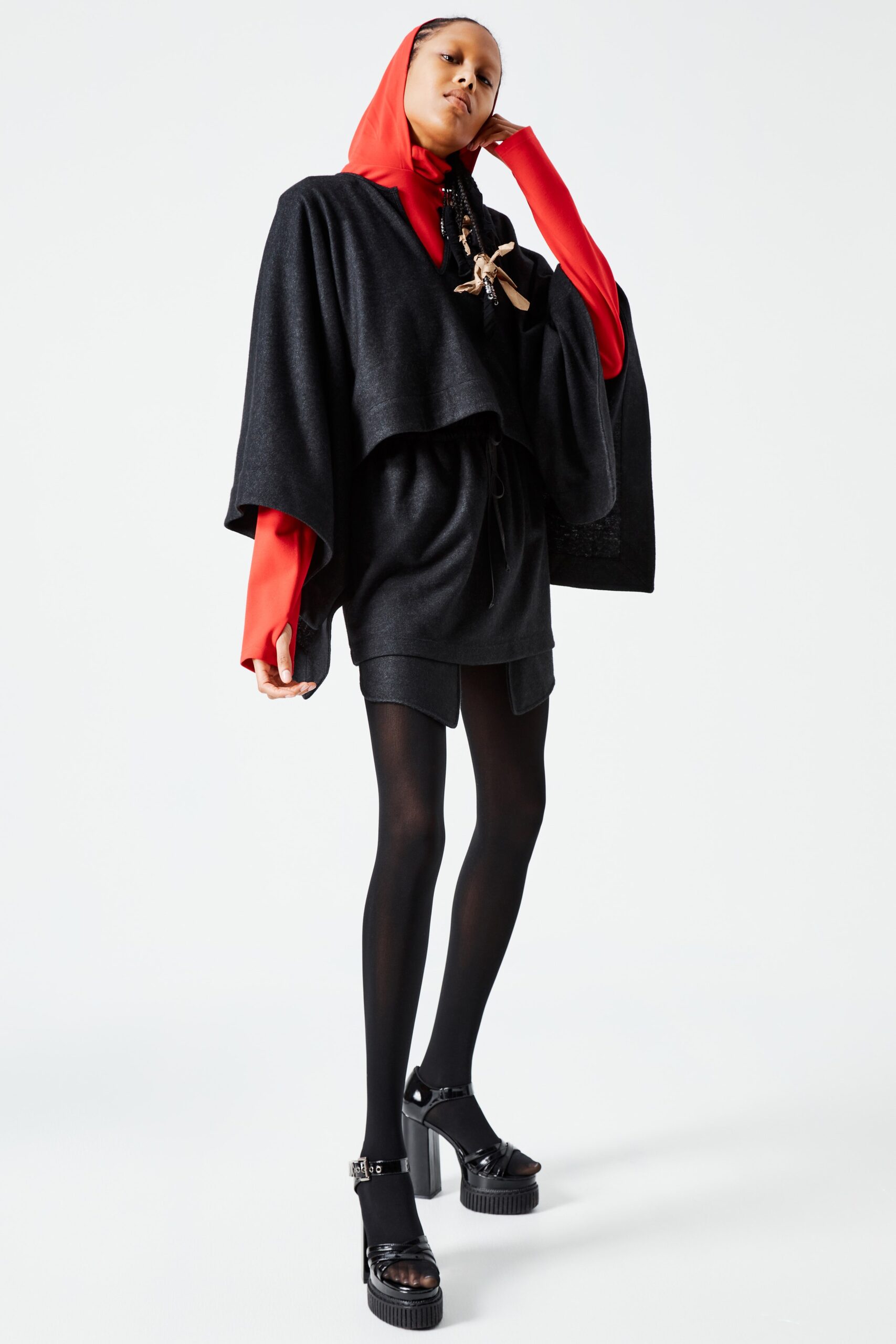 This relaxed poncho dress in black features a high-neck design that adds a contemporary edge. The layered silhouette creates dynamic movement, while the asymmetric cut enhances visual interest, making it a striking addition to any wardrobe.