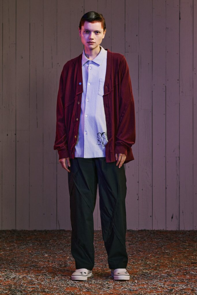 A relaxed white short-sleeve collared shirt paired with black pants featuring button details.