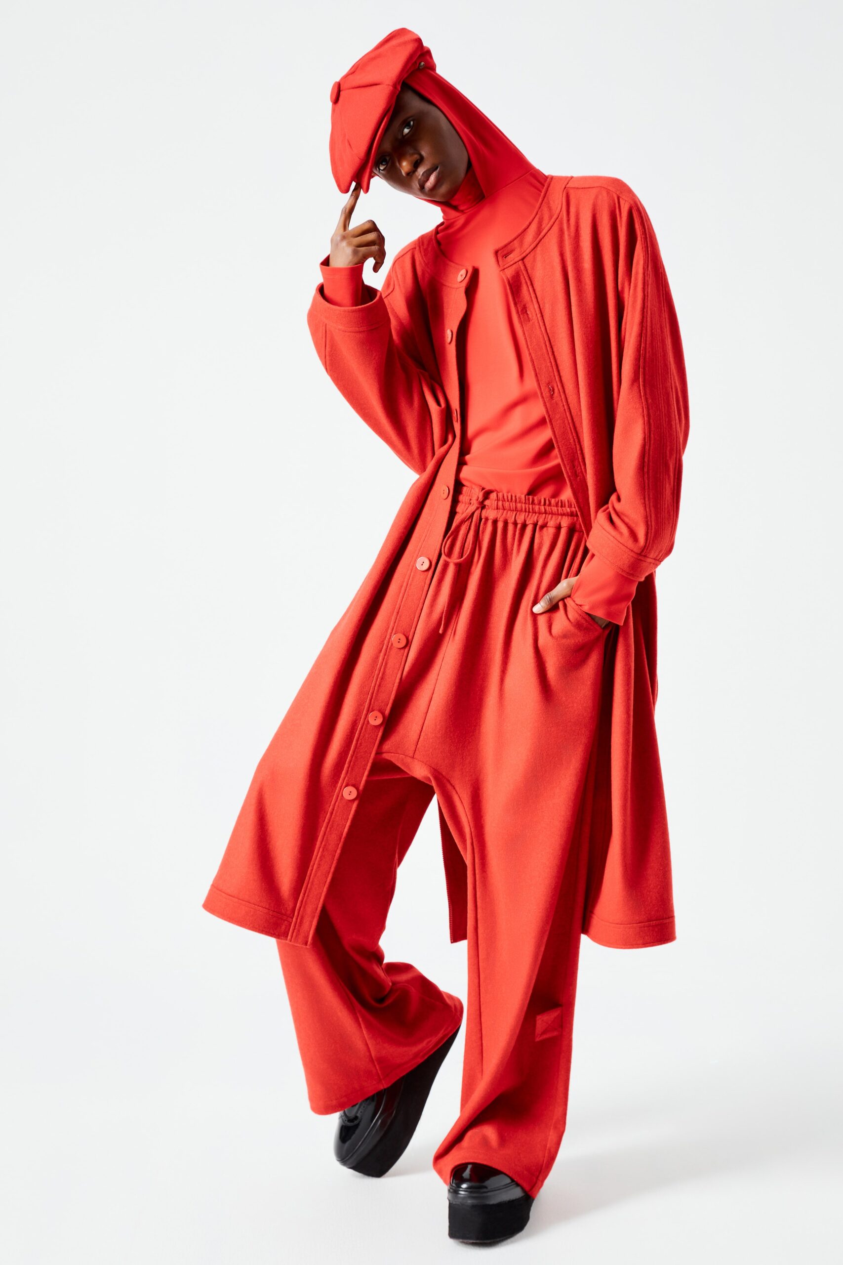 This ensemble features a relaxed coat with a collared neckline and long sleeves, complemented by wide-leg pants. The vibrant red hue creates a bold statement, while the buttoned front adds a touch of structure to the flowing silhouette.
