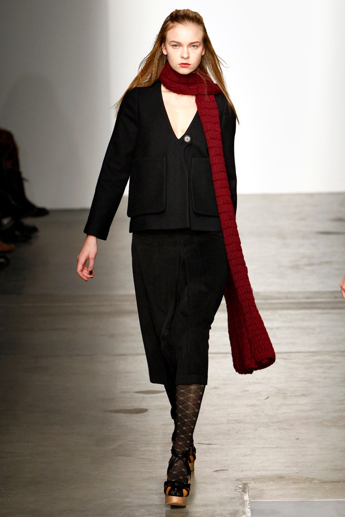 This ensemble features a fitted black dress layered beneath a structured jacket, creating an intriguing interplay of proportions. The V-neckline of the dress adds a hint of allure, while the asymmetric design of the jacket introduces a modern edge to the silhouette.