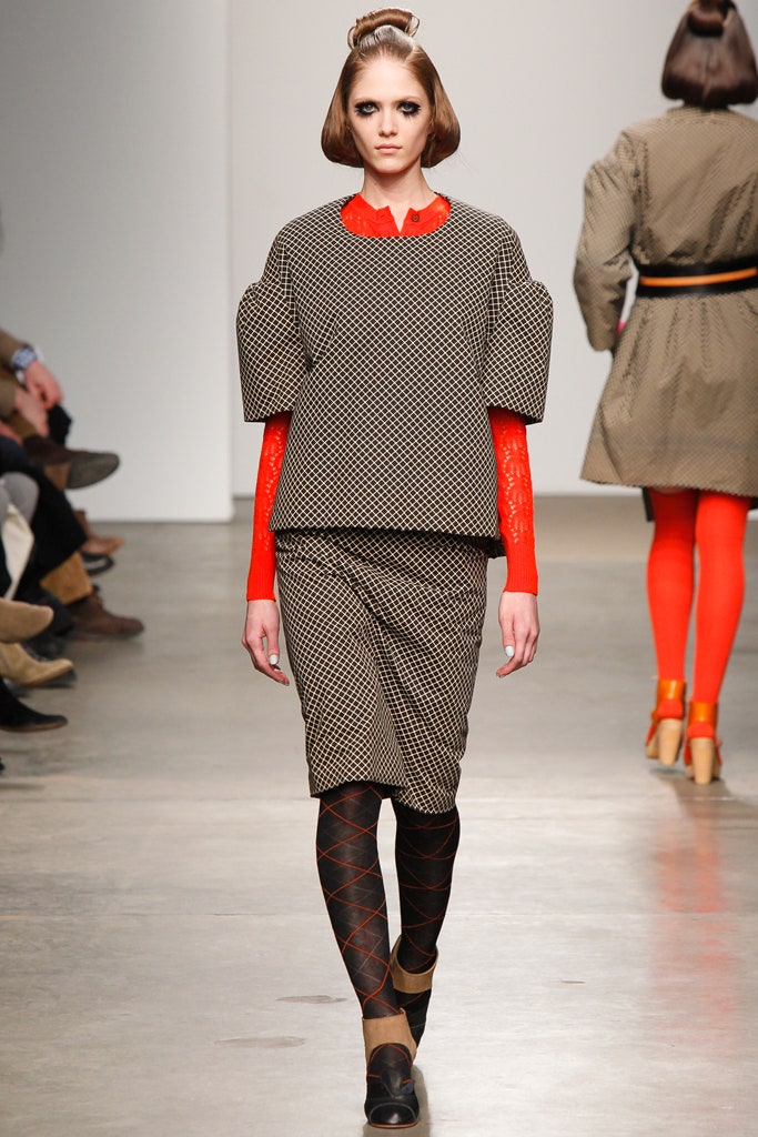 A fitted black printed top with long sleeves and a collared neckline paired with a pencil skirt.