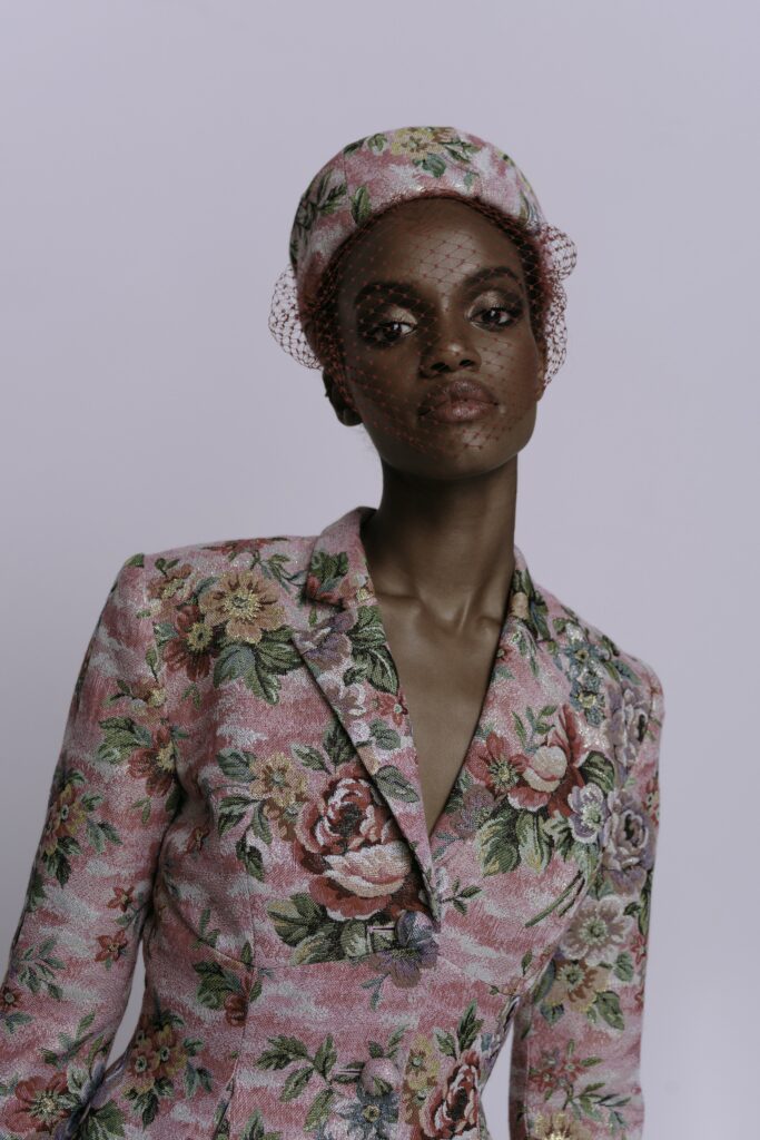 A fitted pink floral blazer with a V-neckline and long sleeves, perfect for a stylish look.