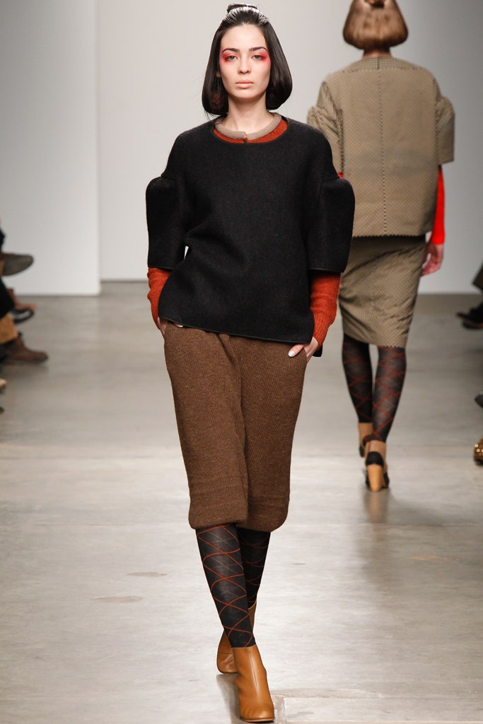 A relaxed black wool long-sleeve top with an asymmetric design paired with a brown skirt.