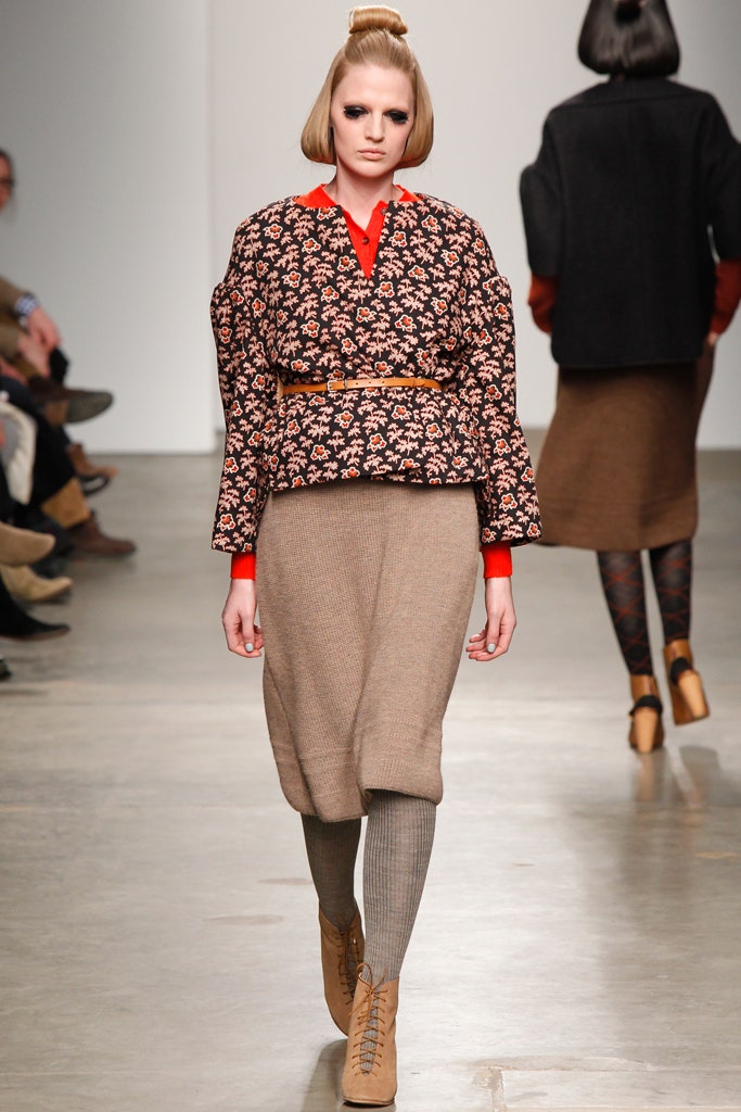 A fitted floral blouse with long sleeves paired with a high-waisted brown skirt.