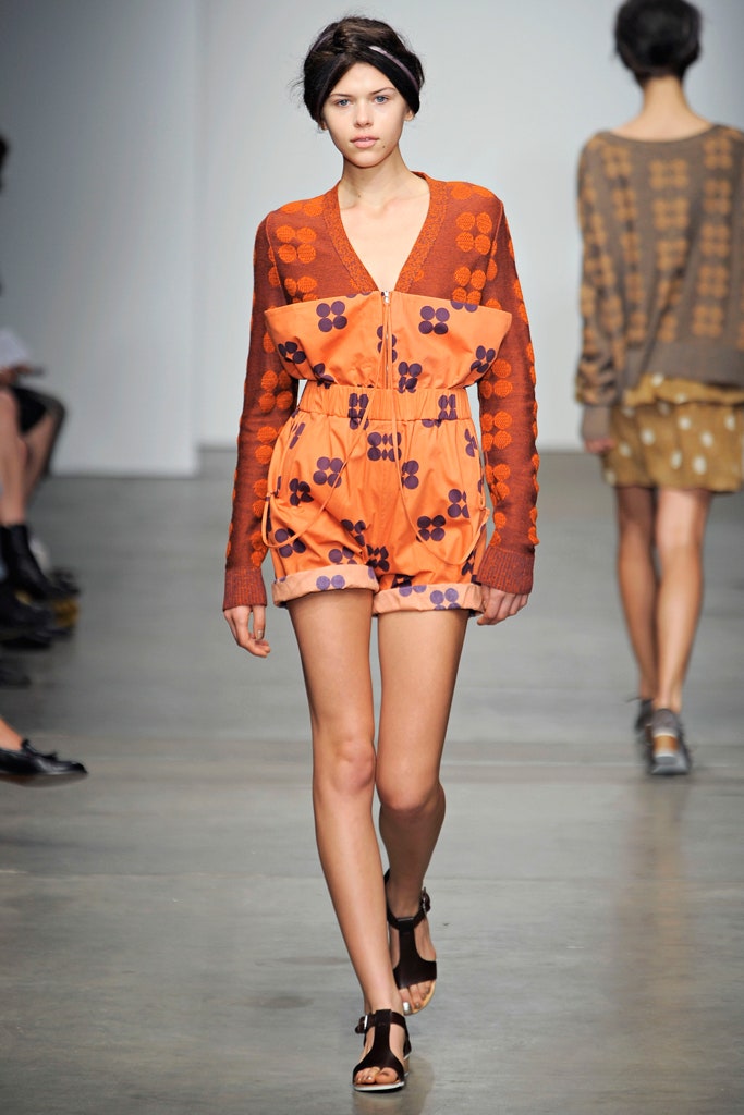 A relaxed orange printed romper with a V-neckline and sleeveless design.