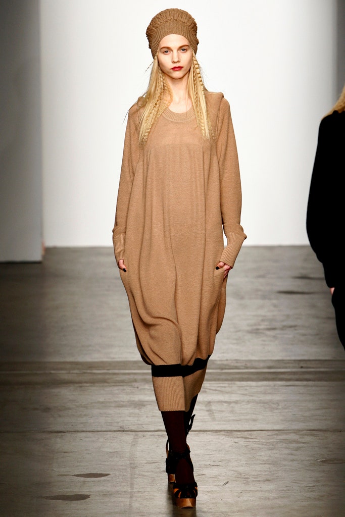 An oversized beige wool dress with long sleeves and a crew neckline featuring a draped design.