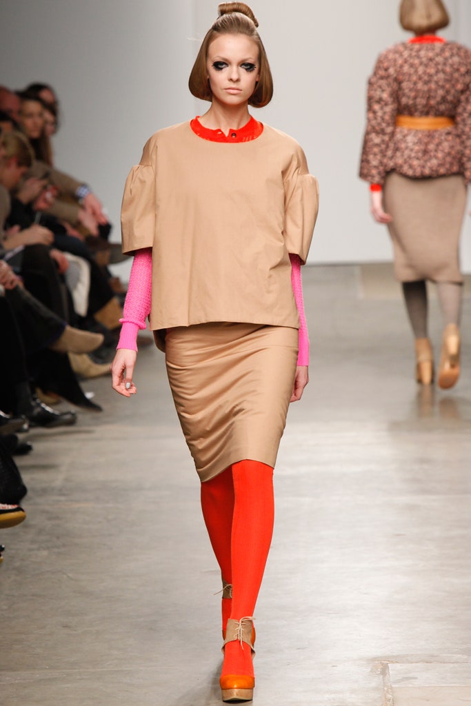 A fitted beige cotton top with short sleeves, paired with a pleated skirt in vibrant colors.