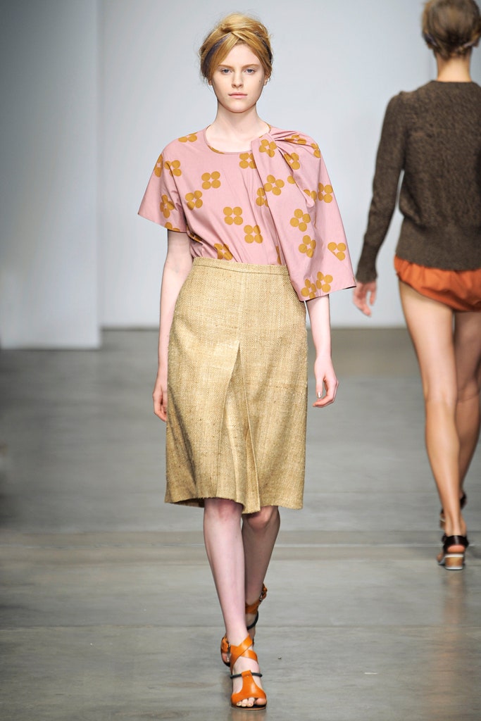 A fitted pink floral top with a short-sleeve design paired with a pleated beige skirt.