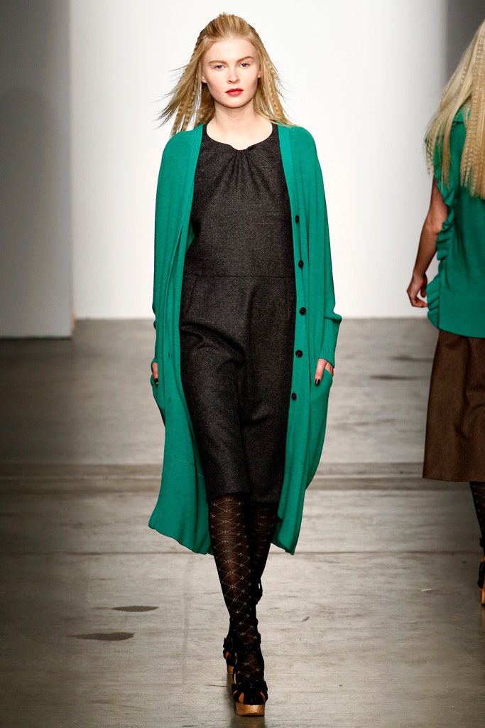 A relaxed black dress layered with a long-sleeve green cardigan featuring button details.