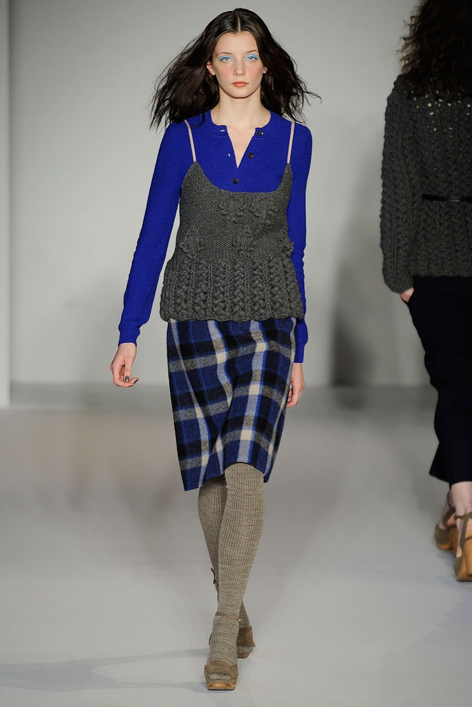 A fitted blue cotton long-sleeve top paired with a gray checked skirt.