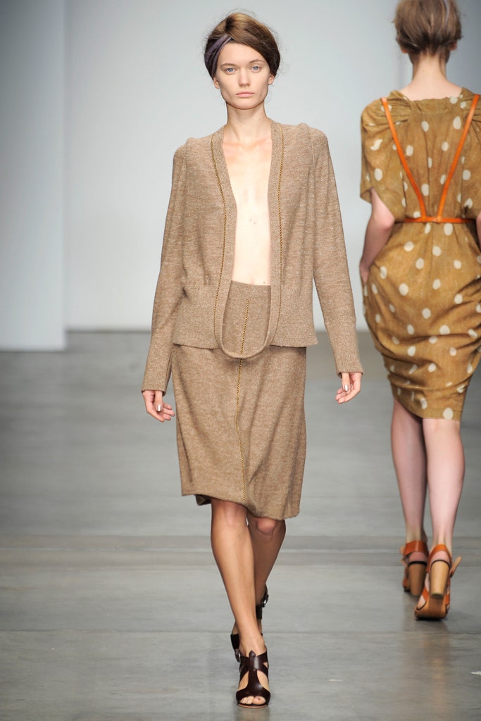 A fitted beige wool jacket with a collared neckline paired with a straight-leg skirt.