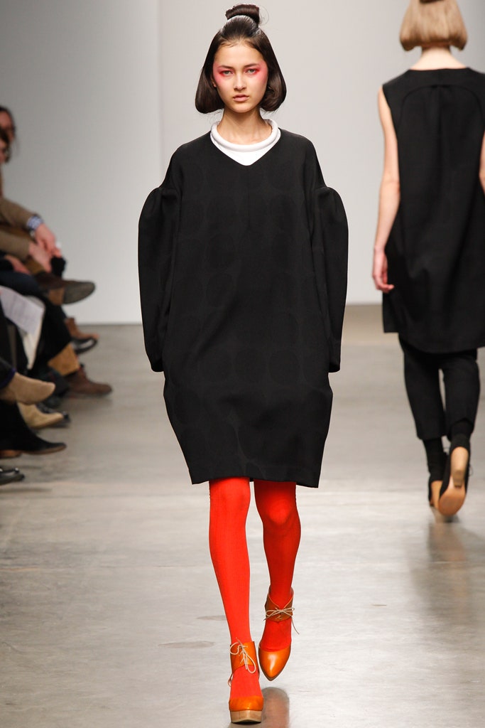A relaxed black cotton dress with long sleeves and an asymmetric design detail.