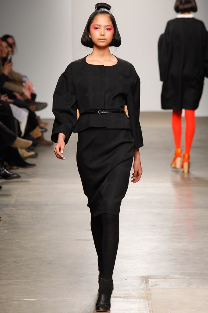 A fitted black dress with long sleeves, a collared neckline, and an asymmetric design detail.
