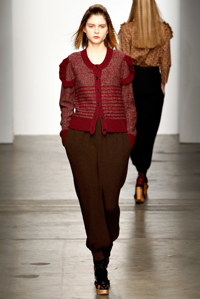 A relaxed-fit burgundy wool cardigan with ruffled details paired with brown relaxed pants.