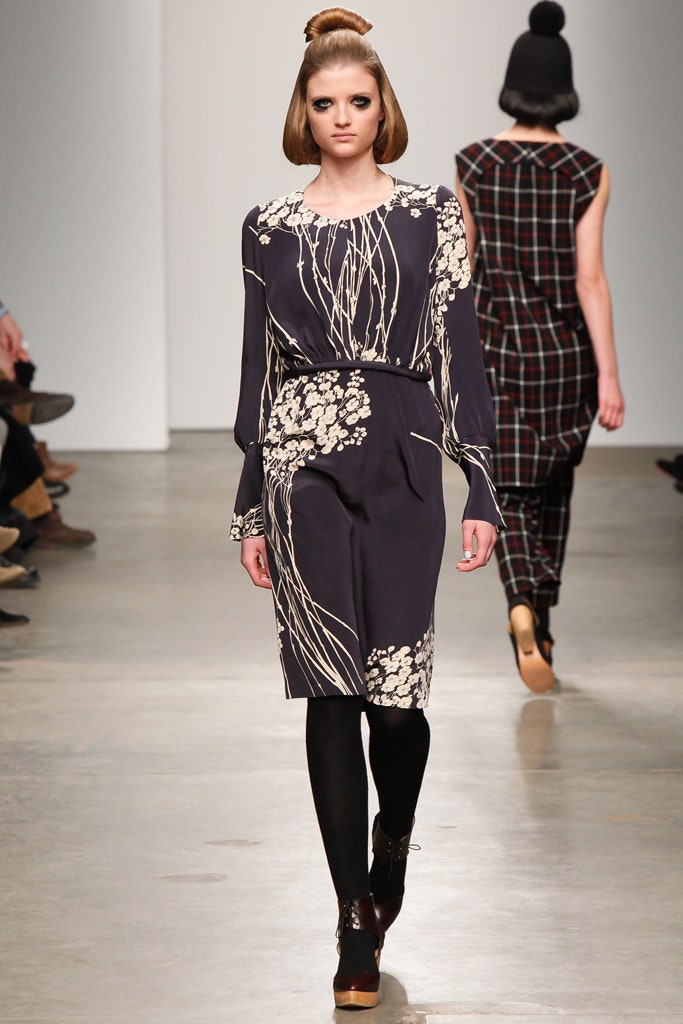 A fitted black long-sleeve dress with a V-neckline and flared silhouette.