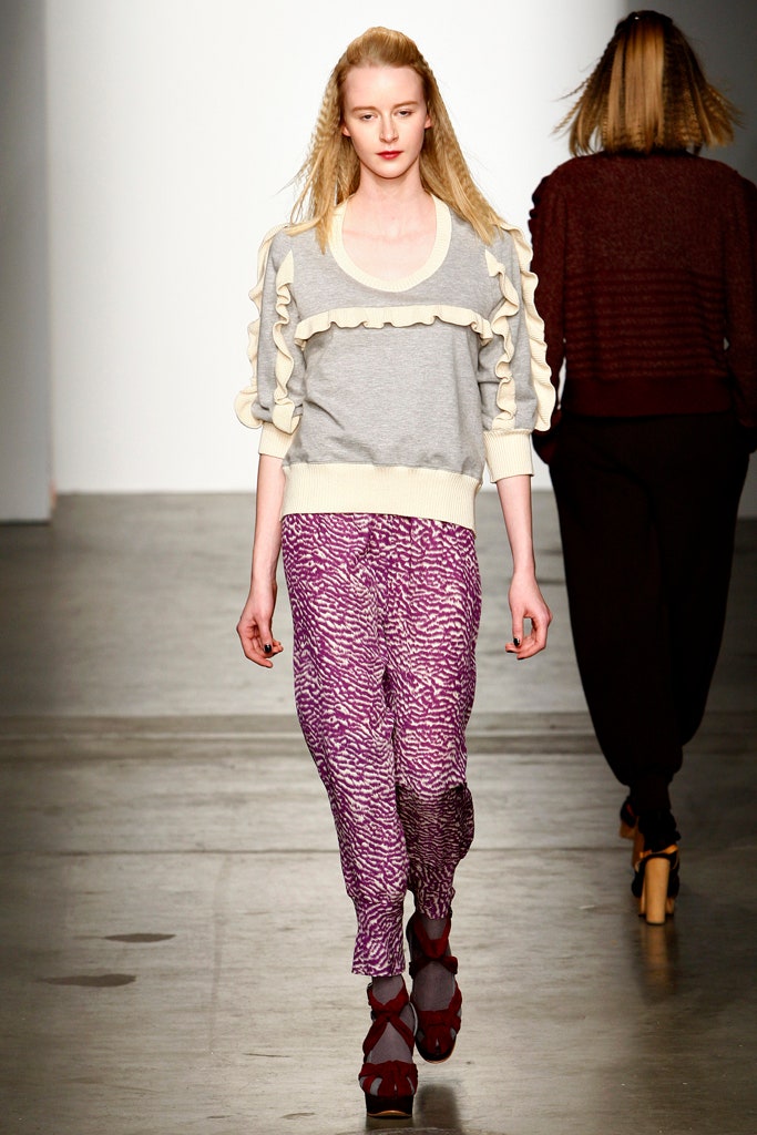 A relaxed gray long-sleeve sweater with ruffled details paired with printed purple pants.