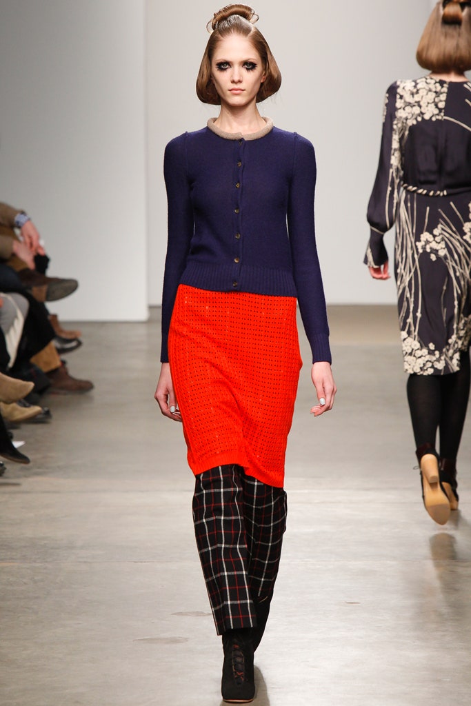 A fitted red dress layered with a navy long-sleeve cardigan, featuring a pencil silhouette.