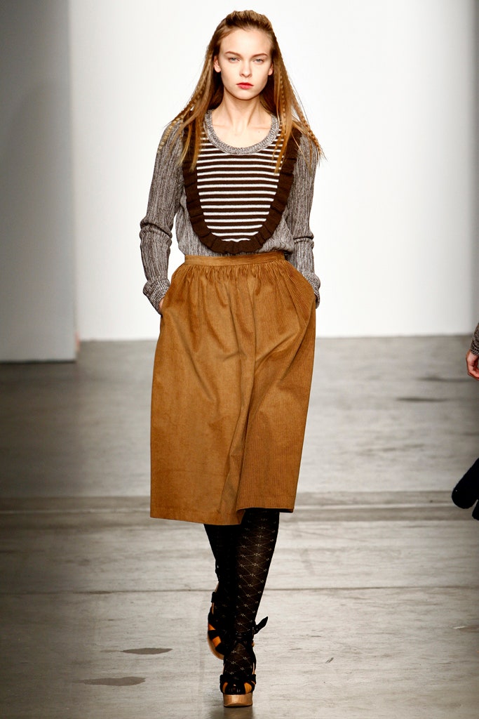 A relaxed outfit featuring a brown pleated skirt paired with a long-sleeve striped shirt.