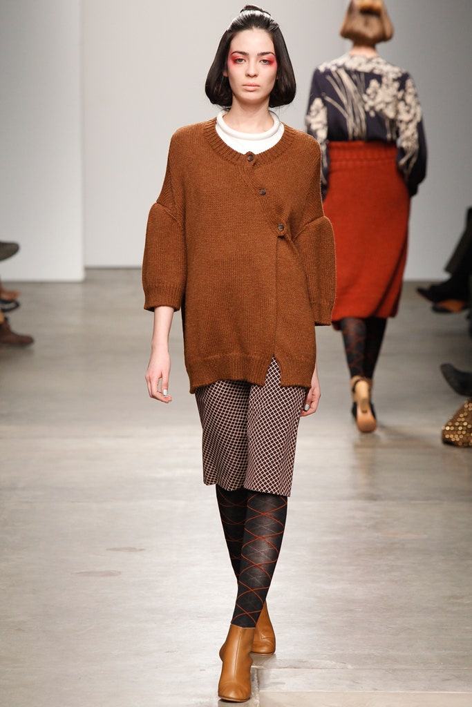 An oversized brown sweater with a button detail paired with a printed skirt.