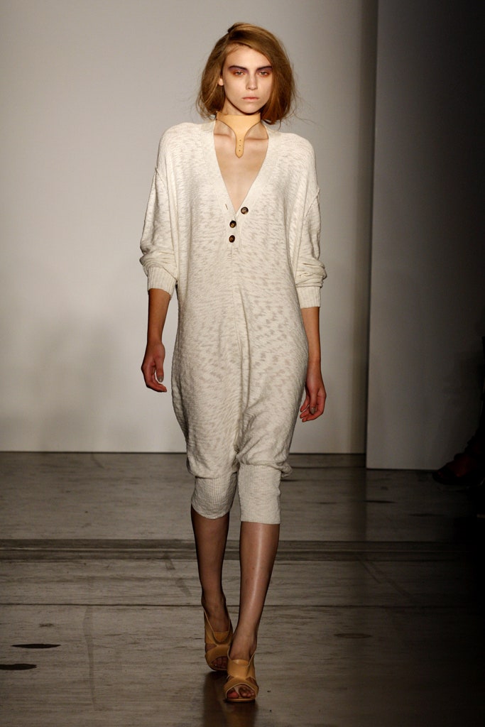 A relaxed beige cotton jumpsuit with a V-neckline and button details.