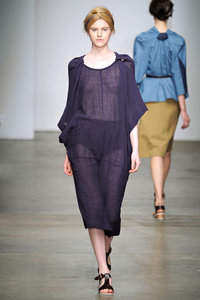 A relaxed blue linen sleeveless dress with a V-neckline and asymmetric design.