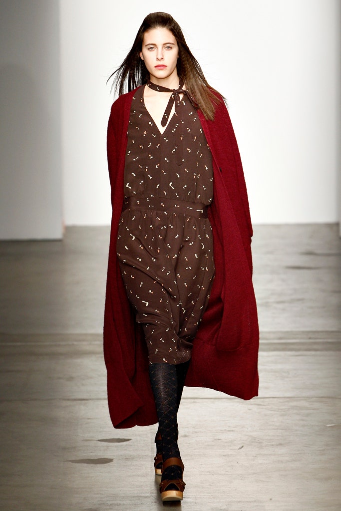 A relaxed brown printed dress layered with a long red coat for a stylish look.
