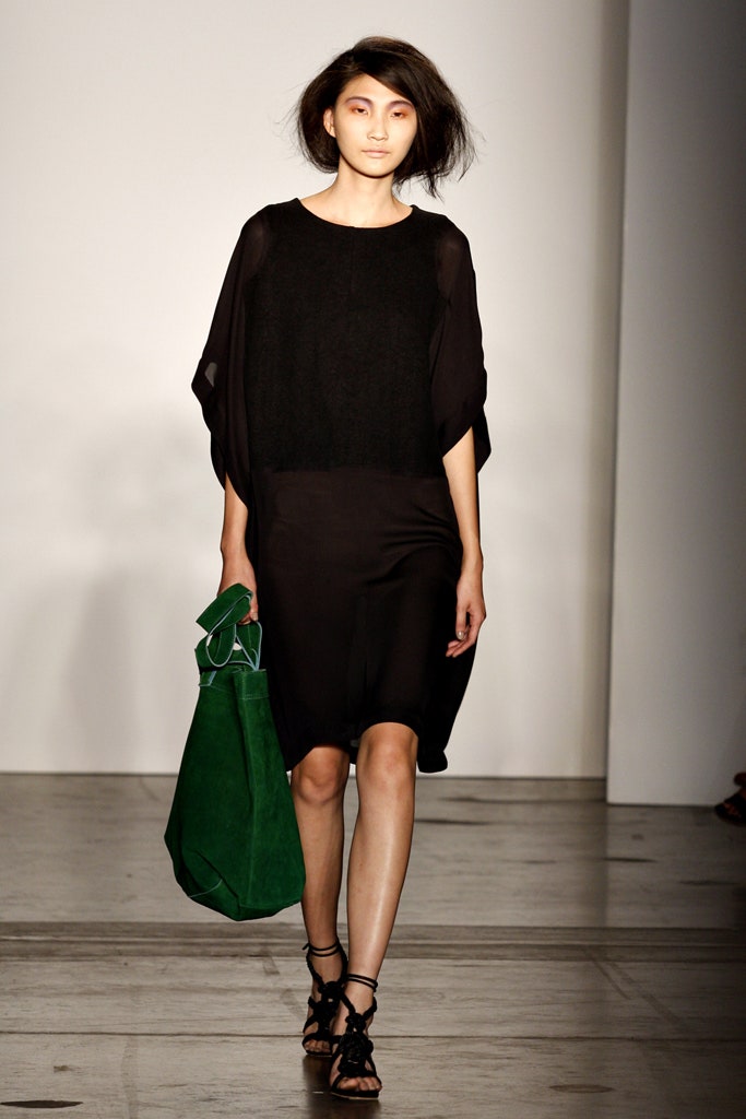 A relaxed black sleeveless dress with a high neckline and asymmetric design.