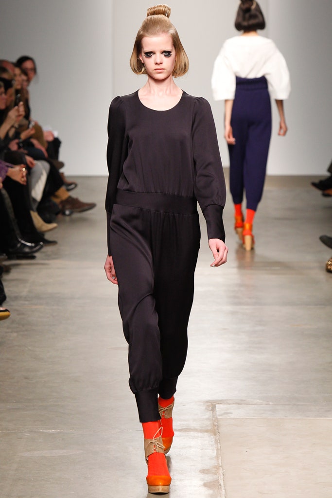 A fitted black silk jumpsuit with long sleeves and a tapered silhouette.