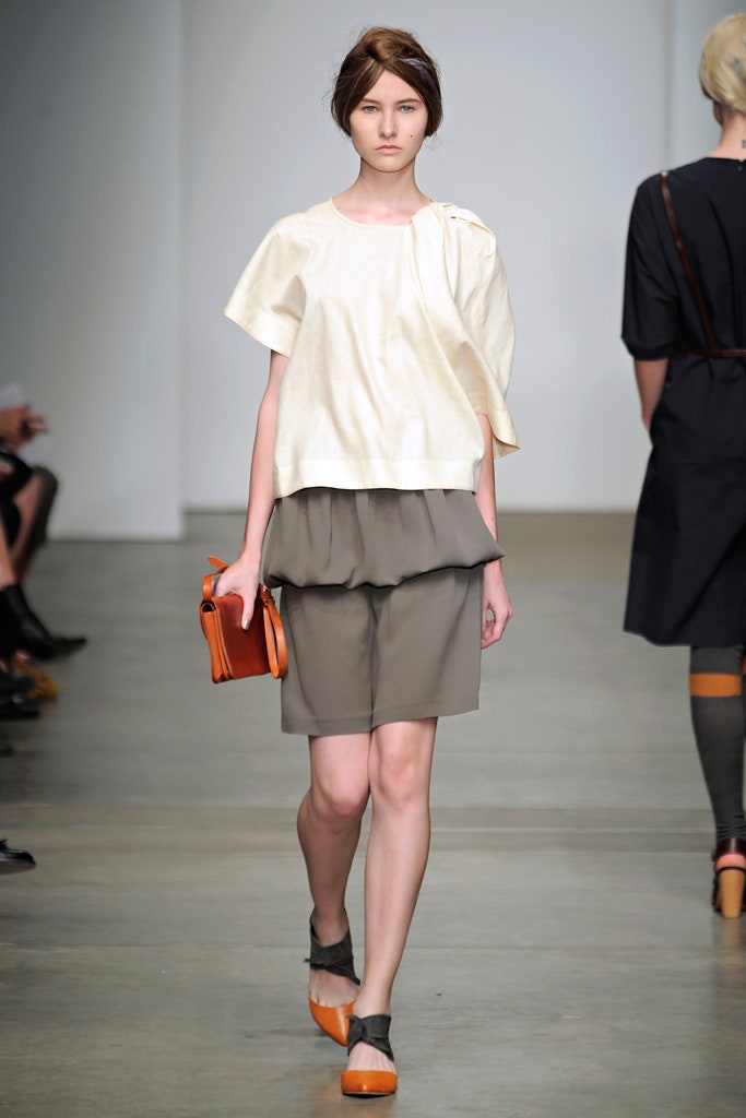 A relaxed beige cotton top with short sleeves layered over a gray skirt.
